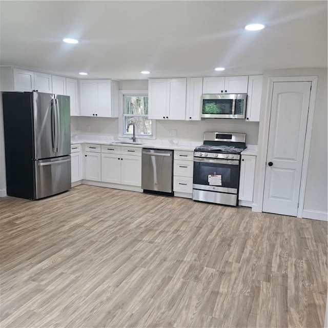 kitchen featuring sink, light hardwood / wood-style floors, white cabinets, and appliances with stainless steel finishes