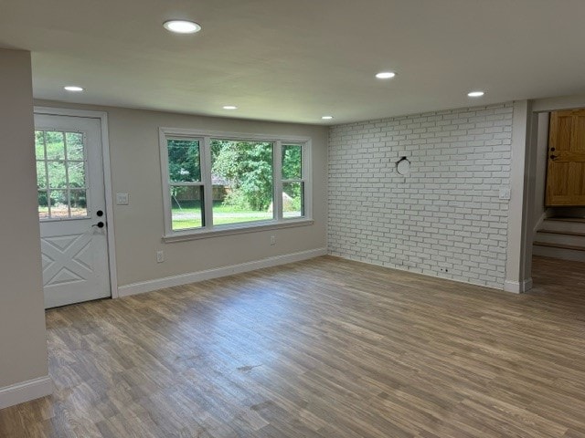 interior space with brick wall and hardwood / wood-style floors