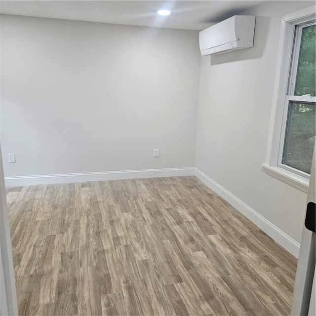 empty room featuring wood-type flooring and an AC wall unit