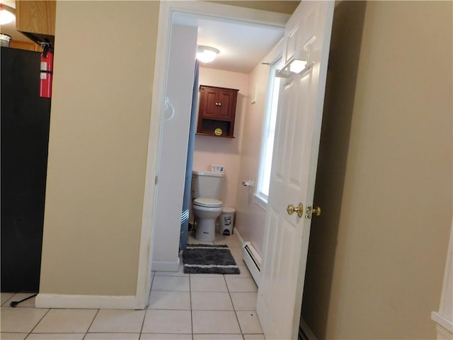 bathroom with toilet, a baseboard heating unit, and tile patterned floors