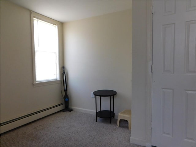 carpeted empty room with a healthy amount of sunlight and a baseboard heating unit