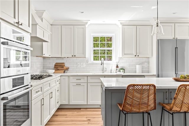 kitchen with a kitchen breakfast bar, light stone counters, white cabinetry, and appliances with stainless steel finishes