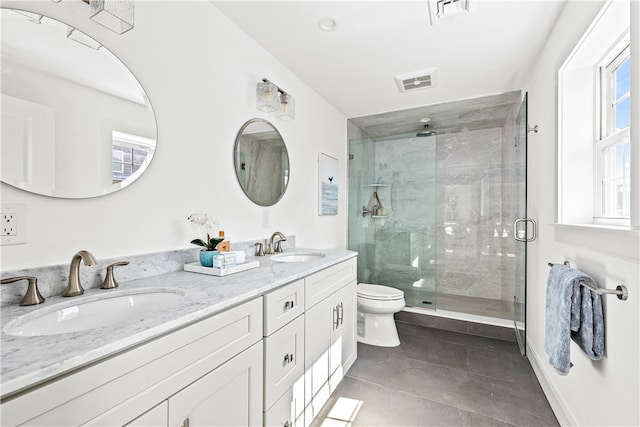 bathroom with tile patterned floors, vanity, a shower with shower door, and toilet