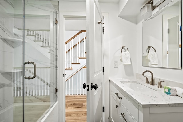 bathroom with hardwood / wood-style floors, vanity, and an enclosed shower