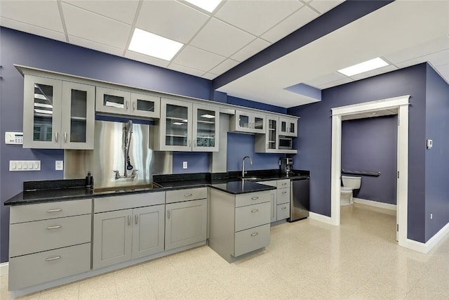 kitchen featuring sink, a paneled ceiling, dark stone countertops, gray cabinets, and dishwasher