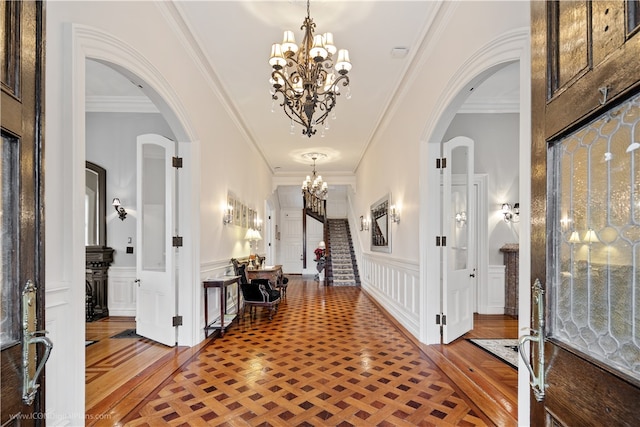 foyer featuring parquet flooring, a chandelier, and crown molding