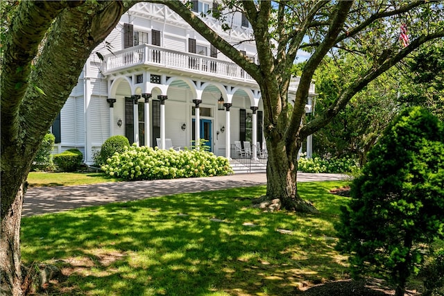 view of front of house with a balcony and a front yard