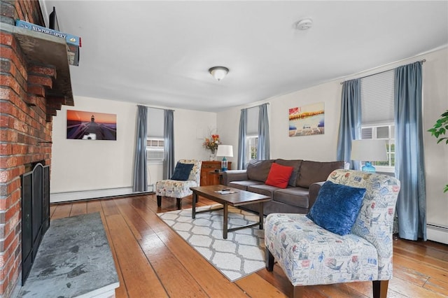 living room featuring light hardwood / wood-style flooring, a brick fireplace, and a baseboard radiator