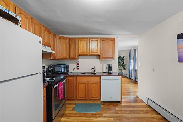 kitchen featuring a baseboard radiator, sink, white appliances, and light hardwood / wood-style floors