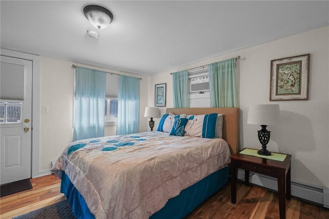 bedroom featuring multiple windows, wood-type flooring, and baseboard heating