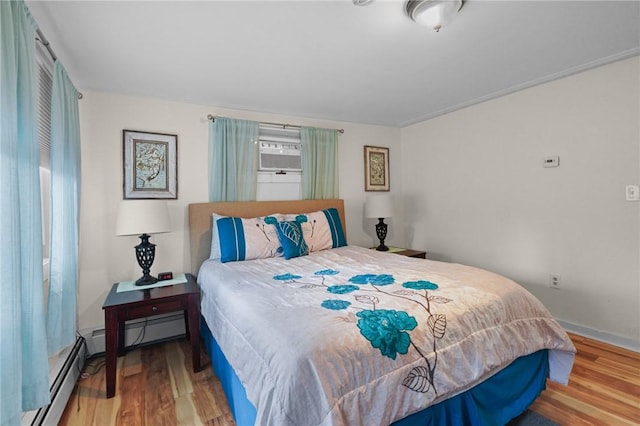 bedroom with wood-type flooring and a baseboard heating unit