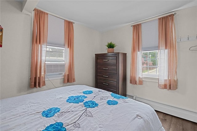 bedroom with cooling unit, wood-type flooring, multiple windows, and a baseboard heating unit