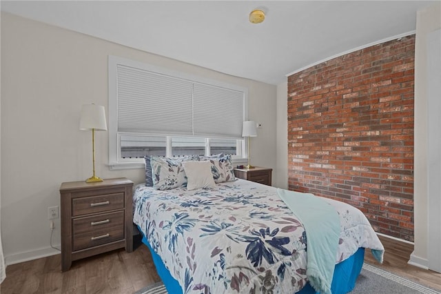 bedroom with brick wall and dark hardwood / wood-style floors