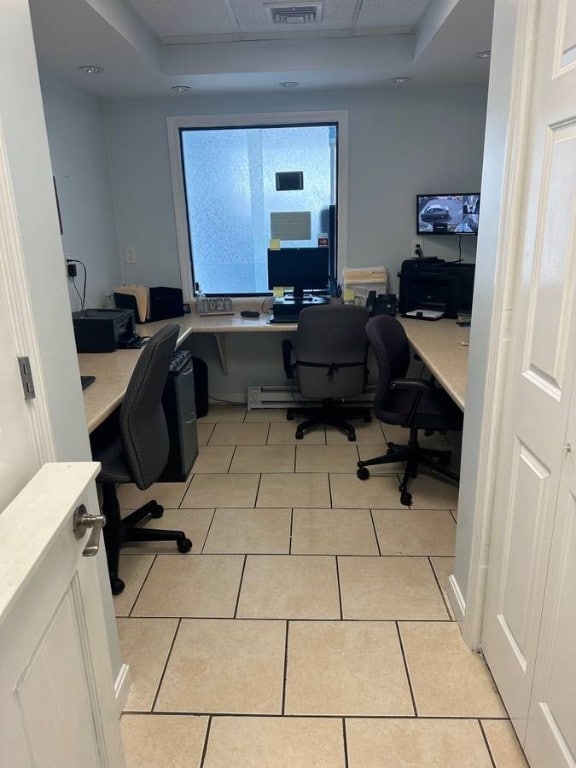 tiled office space featuring a tray ceiling