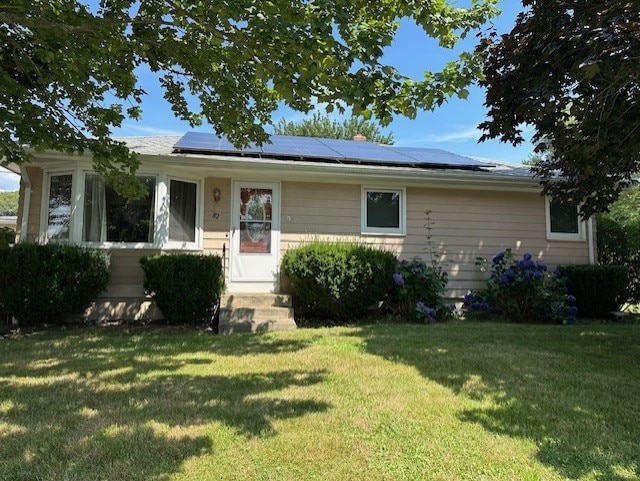 view of front of home featuring a front yard and roof mounted solar panels