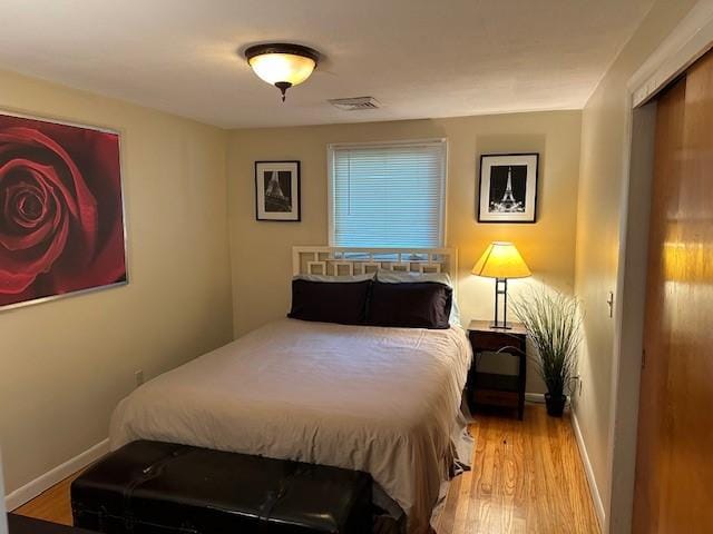 bedroom featuring wood finished floors, visible vents, and baseboards