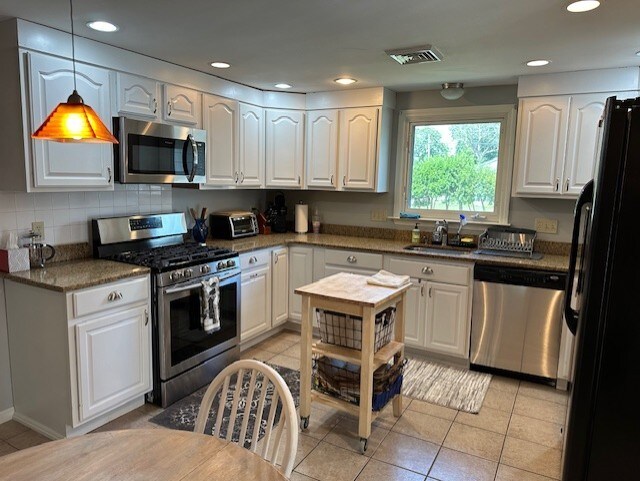 kitchen featuring white cabinets, stainless steel appliances, and pendant lighting