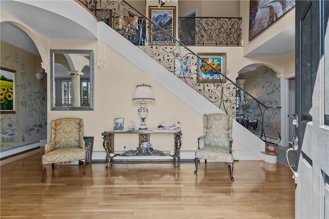 living area featuring a towering ceiling and hardwood / wood-style floors