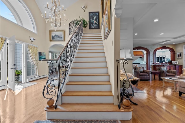 staircase with an inviting chandelier, hardwood / wood-style floors, and plenty of natural light