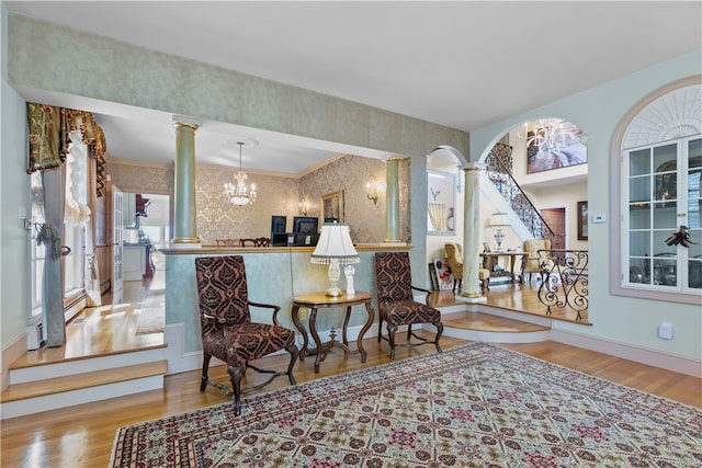 sitting room with decorative columns, light hardwood / wood-style floors, crown molding, and a chandelier