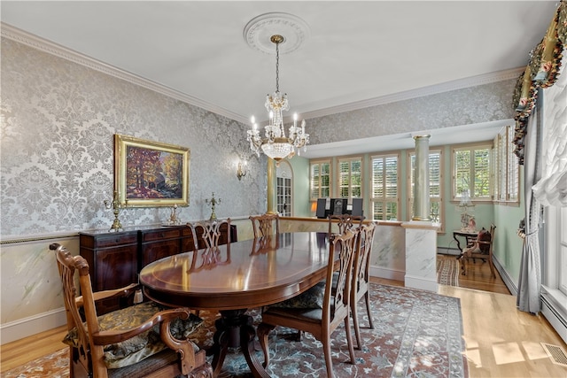 dining room with decorative columns, crown molding, light hardwood / wood-style floors, and a chandelier