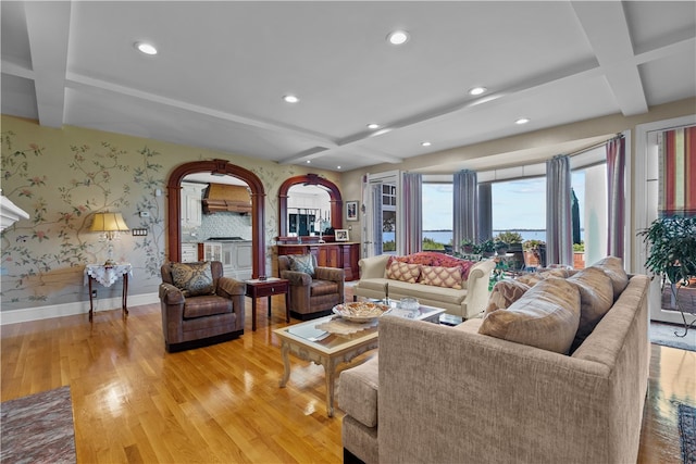 living room featuring light hardwood / wood-style floors, coffered ceiling, and beamed ceiling