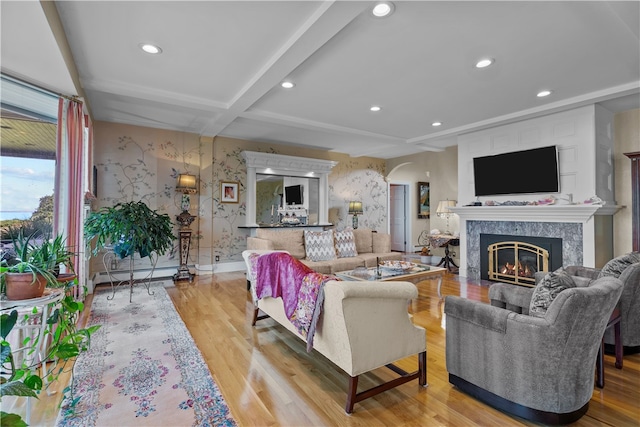 living room featuring beam ceiling, baseboard heating, a high end fireplace, and light hardwood / wood-style flooring