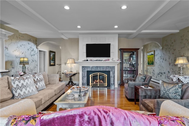 living room featuring coffered ceiling, a fireplace, beamed ceiling, a baseboard radiator, and hardwood / wood-style floors