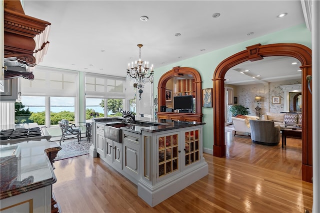 kitchen with light wood-type flooring, hanging light fixtures, sink, and a notable chandelier