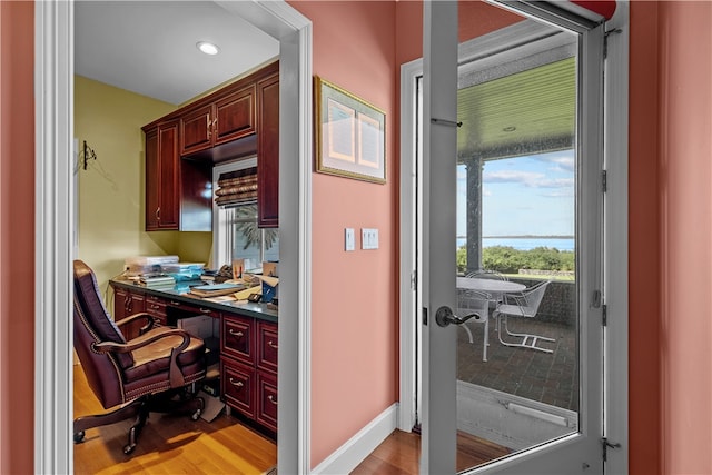 home office with light wood-type flooring and built in desk