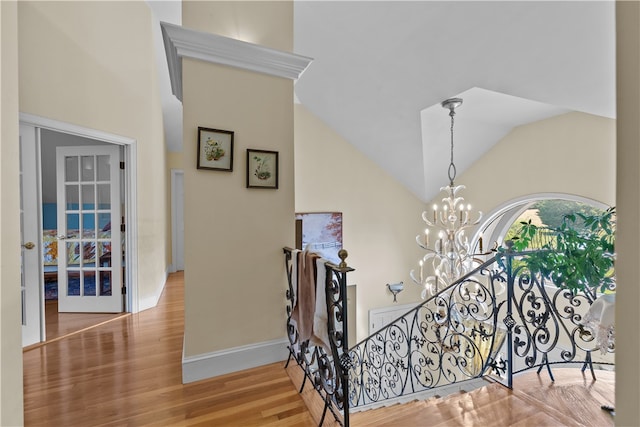 stairs featuring an inviting chandelier, hardwood / wood-style floors, and high vaulted ceiling