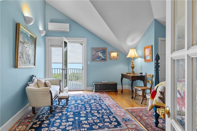 sitting room featuring vaulted ceiling, hardwood / wood-style flooring, and a wall mounted AC