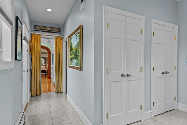 corridor with light tile patterned floors and a baseboard radiator