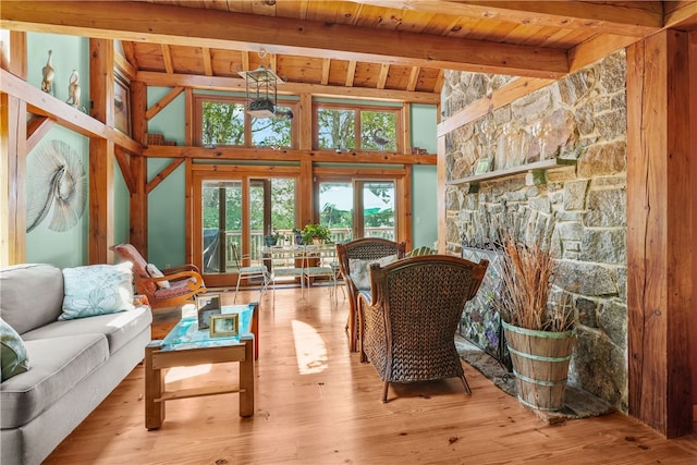 living room with lofted ceiling with beams, a fireplace, light hardwood / wood-style floors, and wooden ceiling