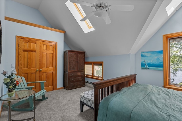 bedroom with lofted ceiling with skylight, light carpet, and ceiling fan