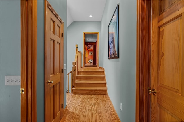 hall with light hardwood / wood-style flooring and lofted ceiling