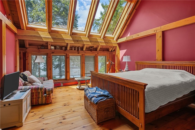 bedroom with high vaulted ceiling, a skylight, and light wood-type flooring