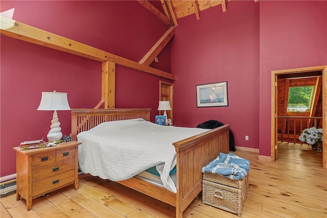 bedroom featuring hardwood / wood-style floors, beam ceiling, and high vaulted ceiling