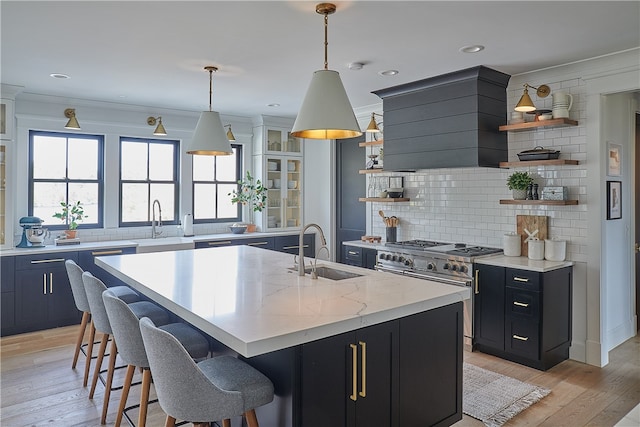 kitchen featuring tasteful backsplash, sink, stainless steel range, a breakfast bar, and a kitchen island with sink