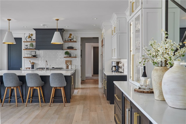 kitchen featuring light hardwood / wood-style flooring, tasteful backsplash, decorative light fixtures, light stone countertops, and white cabinetry