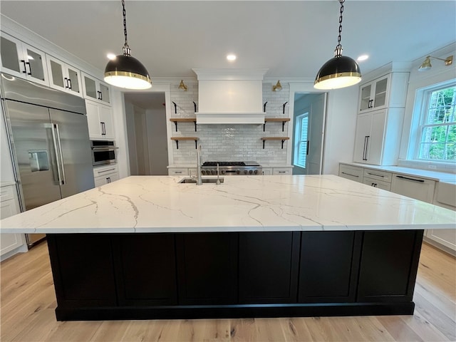 kitchen with decorative backsplash, custom range hood, a spacious island, and light hardwood / wood-style flooring