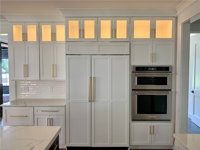 kitchen with white cabinetry, decorative backsplash, light stone countertops, double oven, and paneled refrigerator