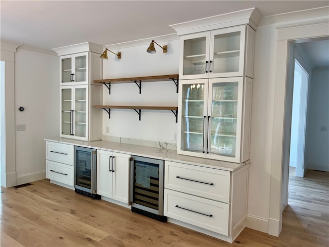 bar with white cabinets, light stone counters, light wood-type flooring, and wine cooler