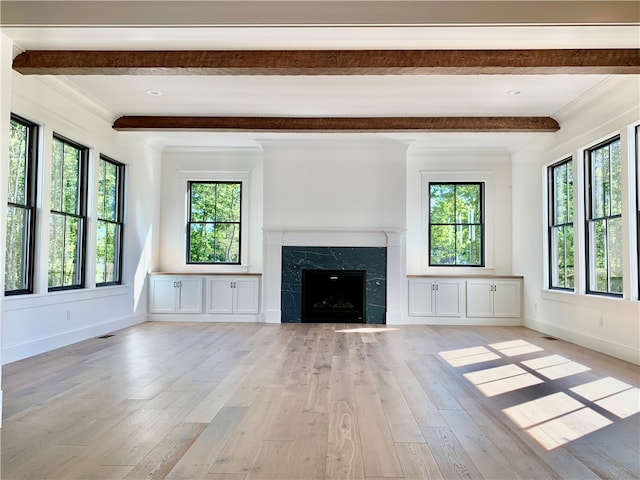 unfurnished living room with a fireplace, beamed ceiling, a healthy amount of sunlight, and light hardwood / wood-style floors