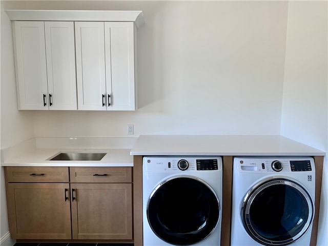 laundry area featuring sink, separate washer and dryer, and cabinets