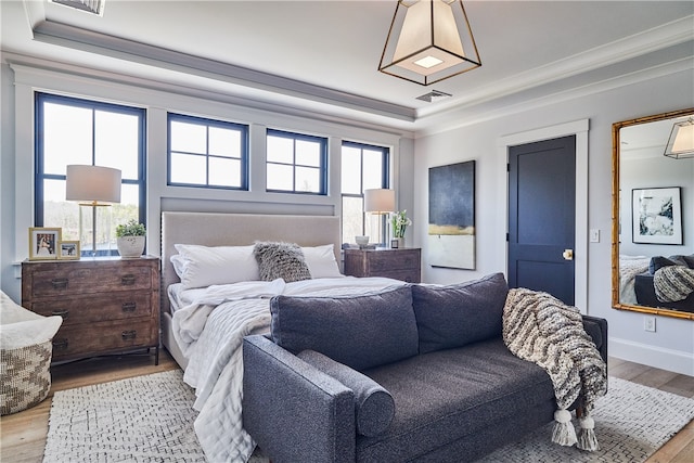 bedroom with light hardwood / wood-style floors and a tray ceiling