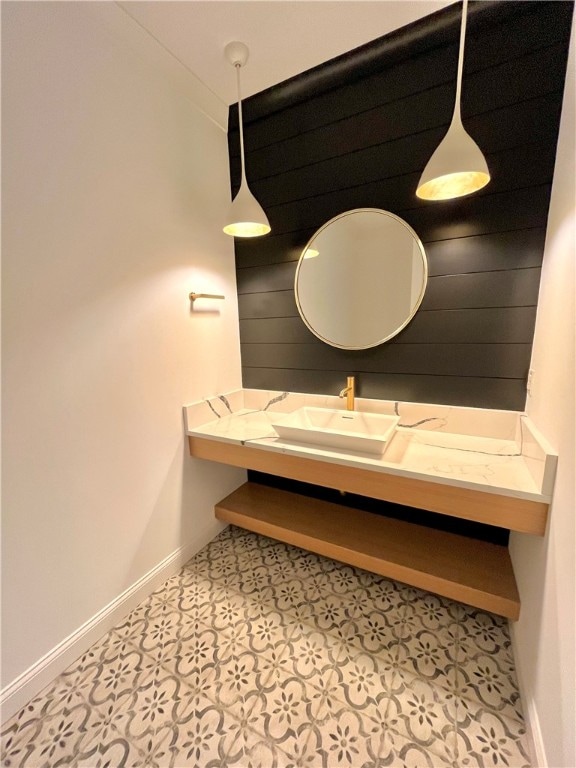 bathroom featuring sink, tile patterned flooring, and wooden walls