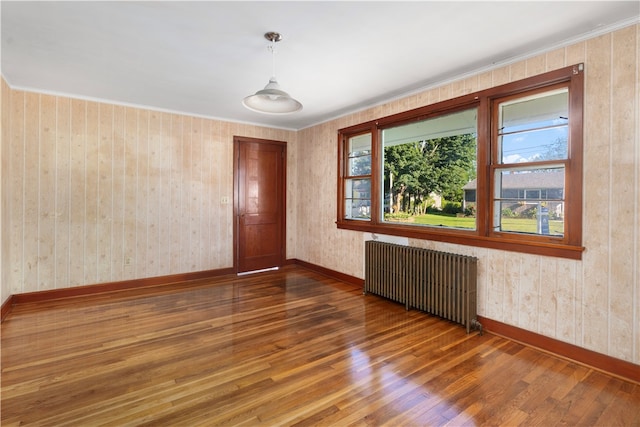 unfurnished room featuring radiator, wood-type flooring, and wood walls