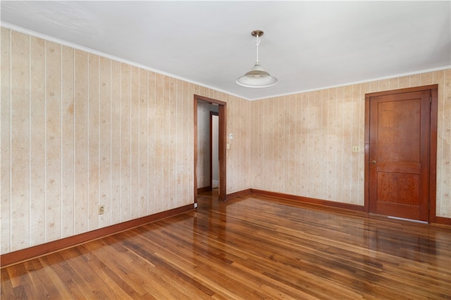 empty room featuring wood-type flooring and ornamental molding