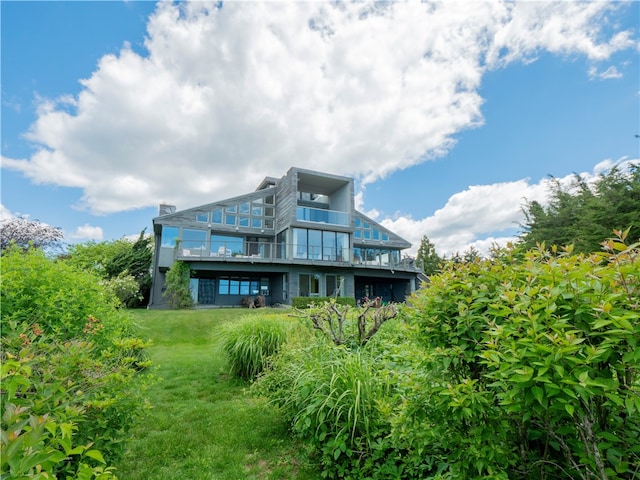 back of property featuring a balcony and a lawn